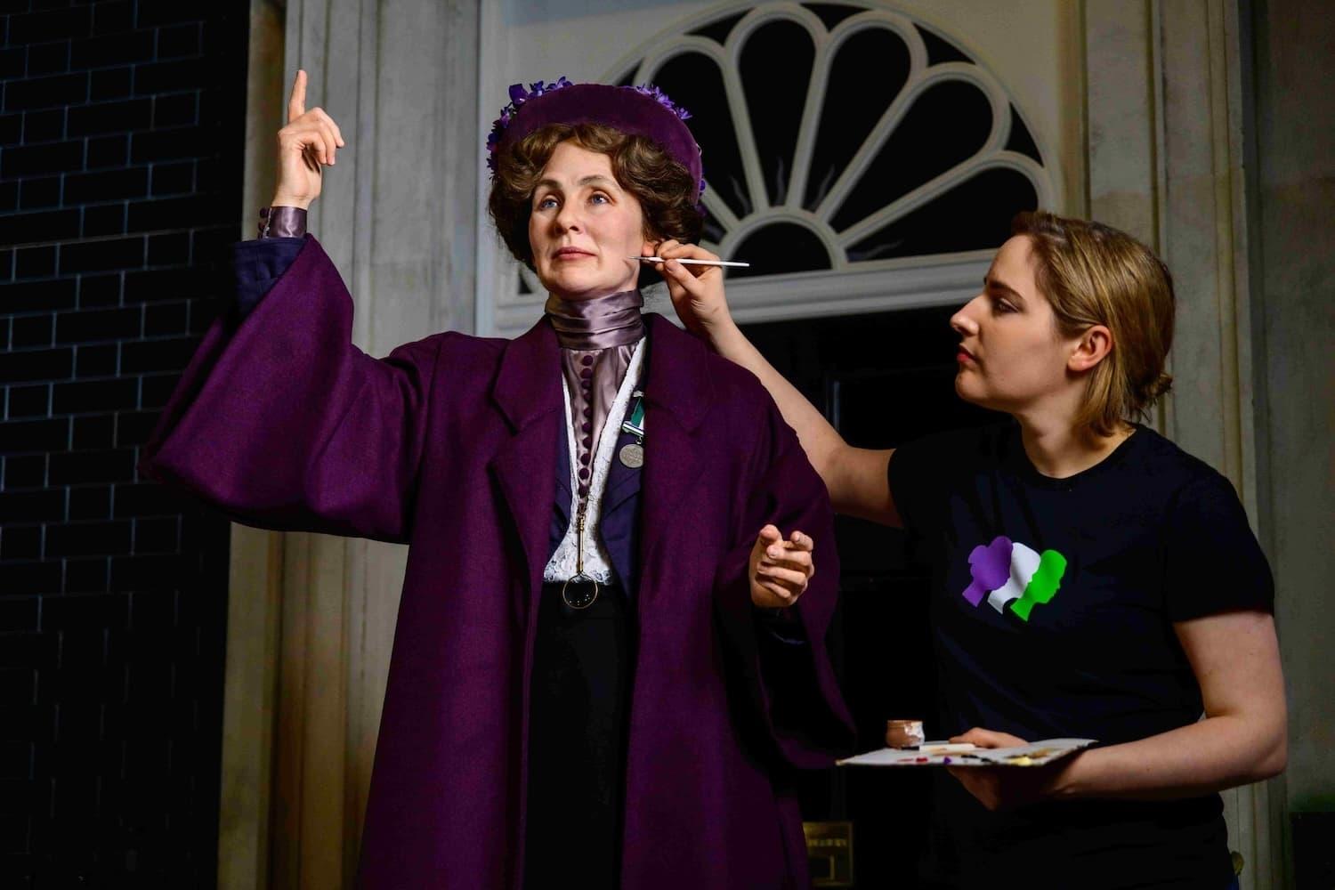 An image of a model maker at Madame Tussauds is painting the face of a figure in a purple costume.