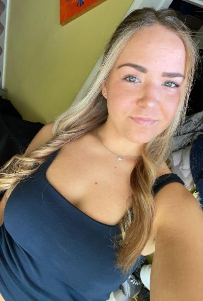 Blonde women with long hair wearing a navy blue tank top posing for a selfie.