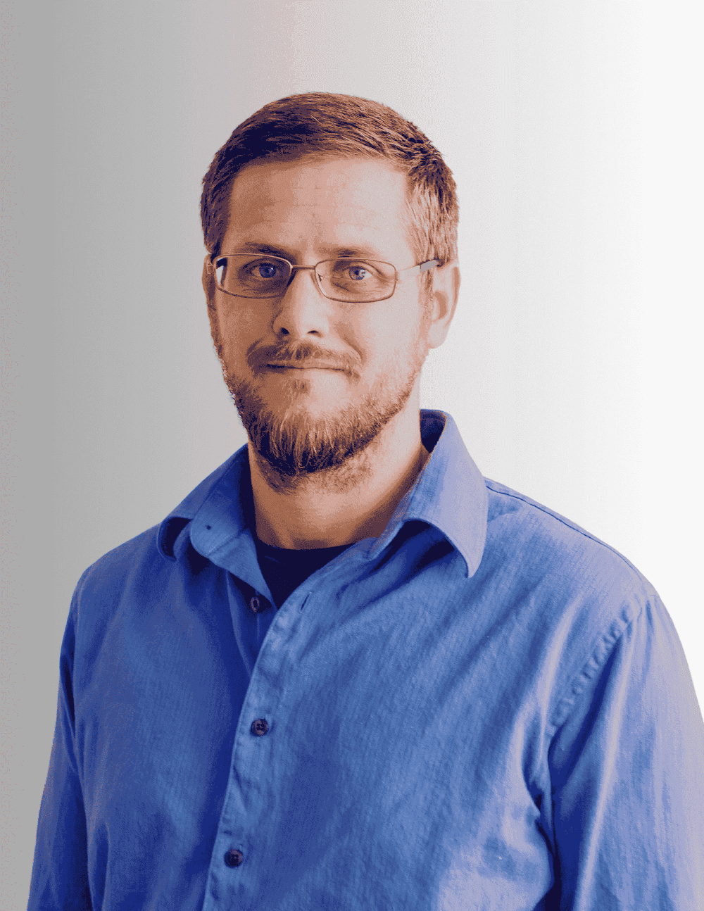 Matt is an administrative assistant, smiling forward wearing a blue shirt and glasses. The background is bright white.