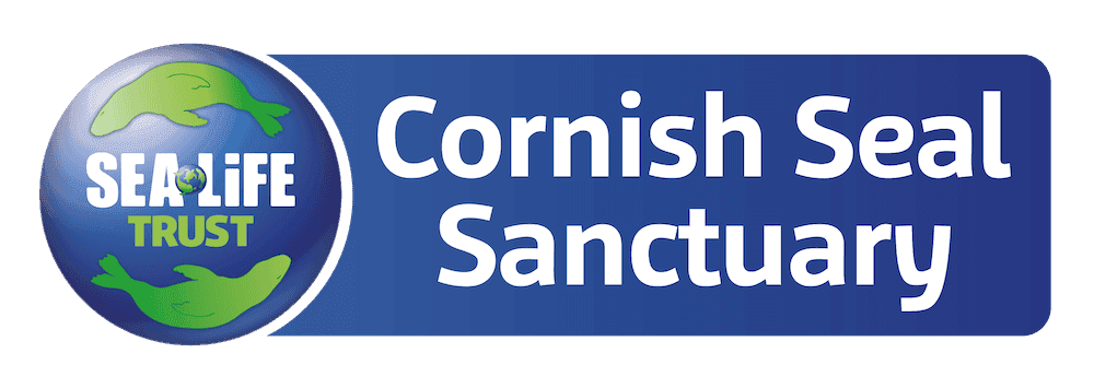 A blue circle filled with cartoon marine animals is next to white text on a green background reading Cornish Seal Sanctuary.