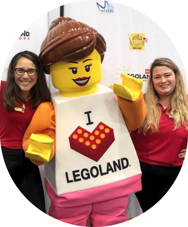 Two woman posing next to a lego figurine