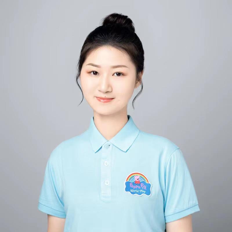 Women in a light, pale blue polo with the Peppa Pig World of Play logo has dark hair in a bun.